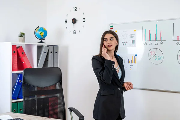 stock image Female worker in suit work at office stand near flipchart and falling by phone, accounting calculate work graph papers