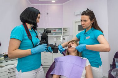 the dentist and his assistant in special clothes take photos of the patient's teeth on the dental chair. Tooth photo concept