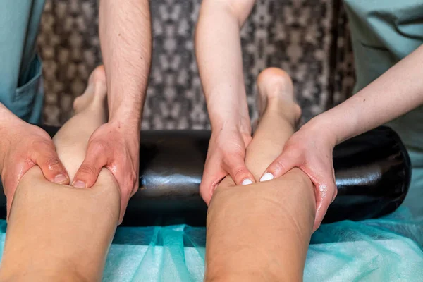 两名按摩师 一名妇女和一名男子 在温泉沙龙为一名女性客户提供四手抗蜂窝腿按摩 用四只手按摩温泉治疗 — 图库照片