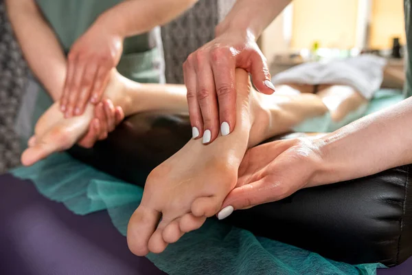 在一个现代美容院里用四只手按摩女性的脚 保健的概念 放松按摩 最好的专家 — 图库照片