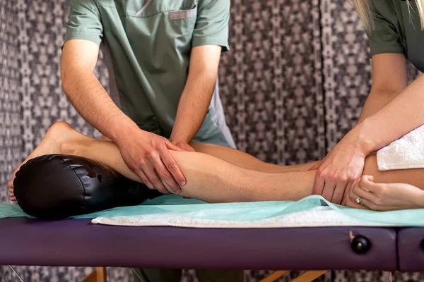 치료사와 남자가 거짓말을 여성을 치료하고 있습니다 손으로 다리를 마사지 의학적 — 스톡 사진