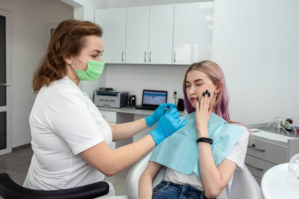 Portrait of a happy female patient sitting in a dental chair next to a young female dentist doctor who is conducting an examination. dentistry.