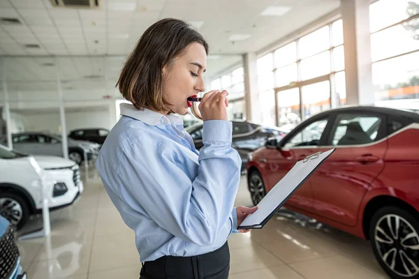 stock image  female salesperson alone at car dealership holding tablet and waiting customer. sale concept