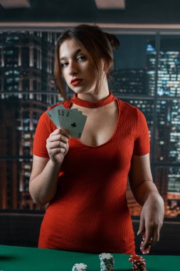 Attractive young woman in a red dress holding a combination of poker cards. poker. Gambling. cards in hands