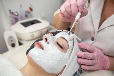 Genç ve güzel bir kadın spa kliniğinde estetik ameliyat oluyor. Deri ve vücut bakımı için yüzünde beyaz maske var. Yaşam biçimi
