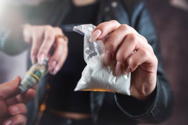 woman addict paying dollar money to drug dealer to buy dose of white powder cocaine. Money exchange for drugs. Drug abuse and traffic concept. 