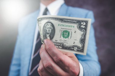 Closeup male hand holding 2 US dollar bills. Money concept 