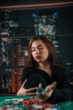 Kadın oyuncu para için fiş sayar ve kumarhanede poker oynarken bahsi artırır. Kumar konsepti. Kadın ve poker. Elbiseli bir kadın.