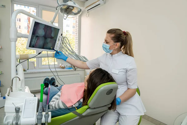 Female dentist examining a female patient teeth with intraoral camera and watch at the screen. Health lifestyle, at the dentist\'s appointment