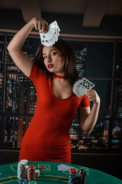 Gyönyörű Sötét Hajú Lány Piros Csábító Ruhában Pókerkártyákkal Kezében Pókerasztal — Stock Fotó