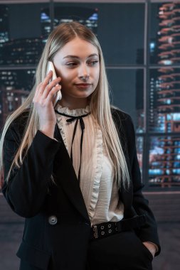 Güzel bayan işçi ofiste duruyor ve telefonda konuşuyor. Moda portresi