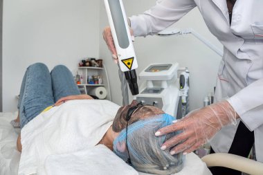 Cildiyeciler, kadın müşterilere sağlıklı cilt için yüz maskesi yapmak için fırçalarını tutarlar. Estetik tıp. kozmetoloji güzellik prosedürleri