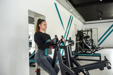 Çekici esmer kız vücudunu eğitmek için simülatör üzerinde egzersiz yapıyor. Crossfit ve güçlü kaldırma eğitimi. Spor. fitness konsepti.