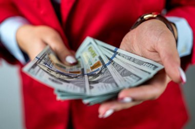 Beyaz gömlekli, kırmızı ceketli ve arka planda izole edilmiş nakit para hayranları tutan bir kadın. Para konsepti. İş. Nakit kar. Dolarlar hazır.