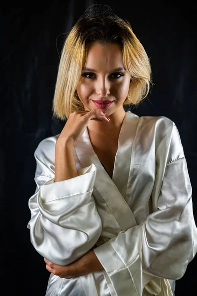 純白の暗い背景に身を包んだ魅惑的なパジャマ姿のセクシーな上品なセクシー女の子 孤立したスタジオの肖像画です — ストック写真