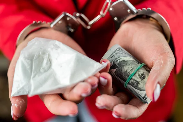 Female fragile hands in handcuffs with dollars in hands. the concept of breaking the law. handcuffs on hands