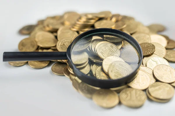 Magnifying glass on a pile of money coins on a glass office table. financial position. economic analysis