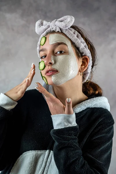 Rosto Cliente Feminino Máscara Barro Branco Mitigando Segurando Fatias Pepino — Fotografia de Stock