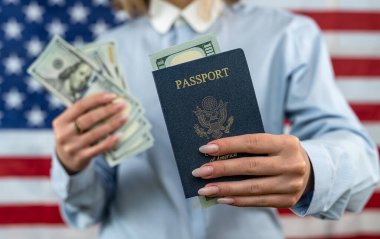 tourist woman on vacation holding United States passport with dollars very happy and excited. woman with passport and dollars in front of usa flag. travel concept