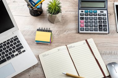 Ofis masası geçmişi, dizüstü bilgisayarı, boş not defteri, kalem hesap makinesi ve malzemeleri. Üst görünüm, iş geçmişi