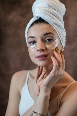 Göz bandı takmış mutlu bir kız siyahın üzerinde yaşlanma karşıtı prosedürler uyguluyor. Cilt bakımı