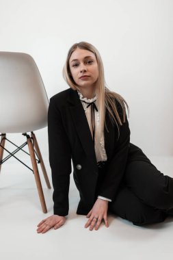 Siyah takım elbiseli, gülümseyen beyaz kadın portresi beyaz zeminde tek başına duruyor. Moda portresi