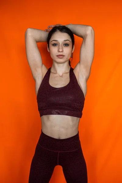 苗条身材的女人穿着用橙色背景隔开的运动服的画像 运动健康生活方式 — 图库照片