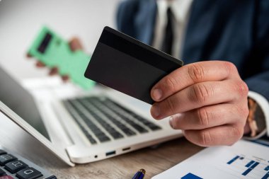Bilgisayarı kullanarak online alışveriş yapmak için kredi kartı tutan bir iş adamı. Kredi kartıyla ödeme, finans konsepti