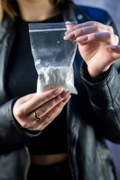 female hand wear dark clothes holds bag with cocaine