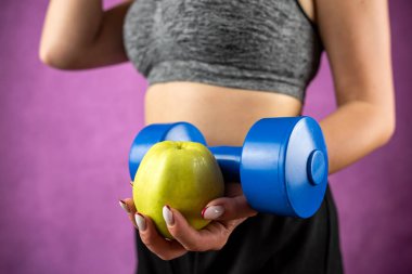 Şerit mezuralı, elinde elma olan zayıf, sportif bir kadın. Kilo kaybı ve sağlıklı yaşam tarzı kavramı