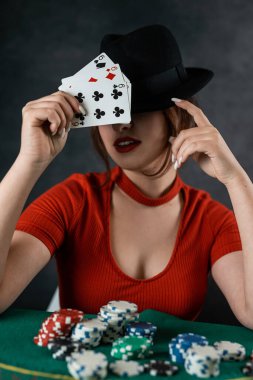Poker oyuncusu elinde kartlarla poker masasında oturuyor ve masada da poker fişleri var. poker. kumarhane