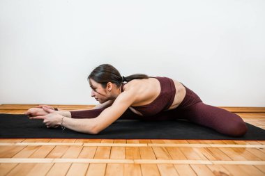Kafkas formda bir kadın stüdyoda yoga minderinde egzersiz yapıyor. Sağlıklı yoga esnemesi