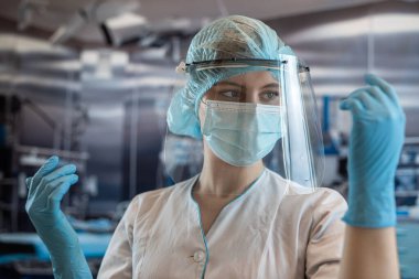 Ameliyathanede ameliyat maskesini takan kadın cerrah ya da asistanın portresi. Coronavirus Covid19 salgını