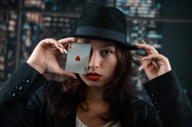 girl in a casino with red lipstick holds playing poker cards near her face at the poker table. poker. casino.
