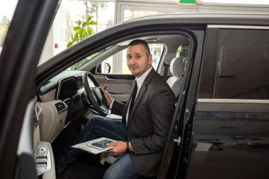 Takım elbiseli adam galeride en iyi yeni arabayı seçiyor. satış veya kiralama konsepti