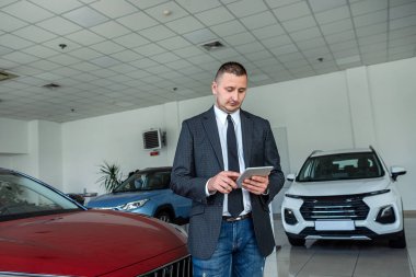  Takım elbiseli genç satıcı galeride müşteri bekliyor. Araba konsepti al. ulaşım