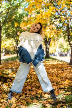 Gülümseyen genç kadın portresi Sonbahar parkında ya da ormanda yürüyor, yaşam tarzında.