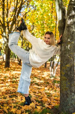 Sonbahar parkında görev yapan genç bir kadın, doğada rahatlama.