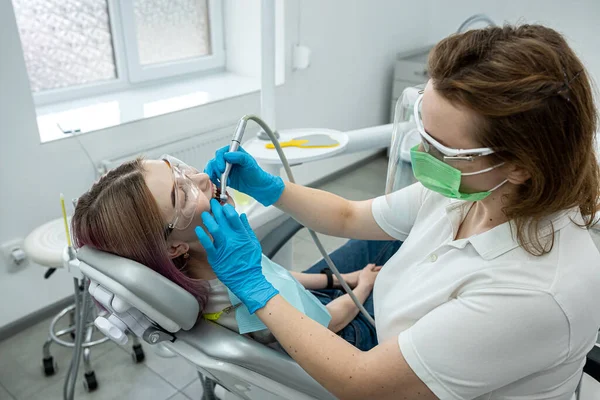Młoda Dziewczyna Siedzi Krześle Medycznym Podczas Gdy Dentysta Leczy Zęby — Zdjęcie stockowe
