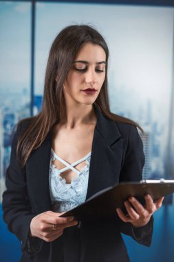 Ofiste poz veren, takım elbiseli, mutlu, kendine güvenen beyaz kadın yönetici. Başarılı bir iş kadını.