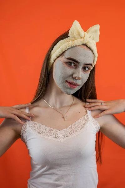 얼굴에 초록색으로 자양분 마스크를 여성의 초상화가 오렌지색으로 고립되어 있습니다 — 스톡 사진