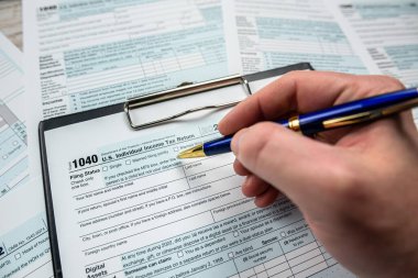 Close up man filling 1040 individual income tax form. Tax time. Deadline 
