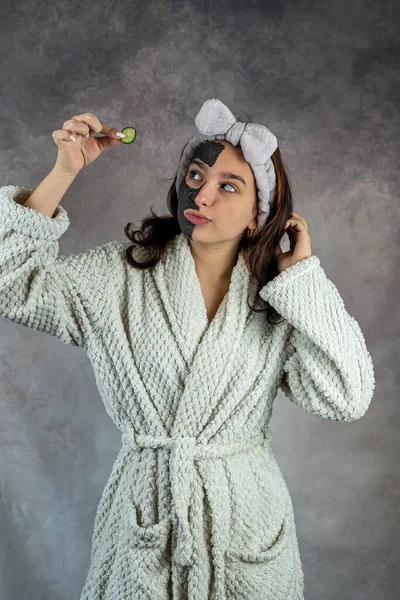 Young Woman White Bathrobe Holding Slices Cucumber Applying Black Clay — Stock Photo, Image