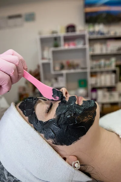 Młoda Ładna Kobieta Otrzymuje Czarną Kosmetyczną Maskę Twarzy Salonie Piękności — Zdjęcie stockowe