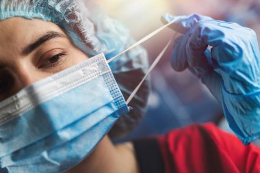 Cerrahi maskeyi çıkartan yorgun bir hemşirenin yakın çekimi. Coronavirus için kapatma kavramı. Hastanede bir vardiyadan sonra kadın doktor.