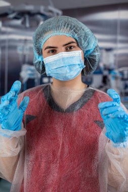 Beyaz kadın doktor hemşire portresi kırmızı üniformalı, mavi maskeli ve siyah eldivenli. 