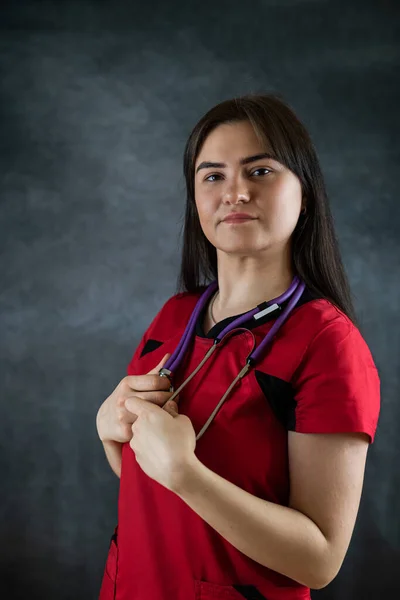 Pracownica Szpitala Czerwonym Mundurze Stetoskopem Patrząca Kamerę Odizolowaną Czarnym Tle — Zdjęcie stockowe