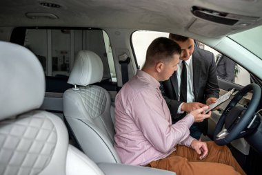 Erkek müşterisi olan arkadaş canlısı bir satıcı satış öncesi veya satış öncesi yeni araba hakkında konuşur ve açıklar, konsept satar