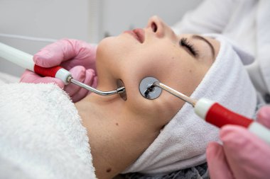 Güzellik uzmanı spa salonunda elektriksel impulslarla yüz işlemleri yapıyor. Cilt bakım spa konsepti