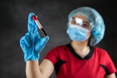 Kadın hemşire ya da doktor kırmızı üniforma giyiyor ve üzerinde koronavirüs COVID-19 izole edilmiş kan testi sonuçları var. Tıbbi araştırma